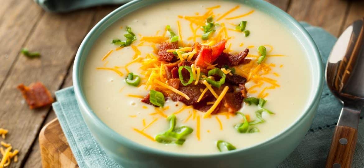Supă cremoasă de cartofi cu fasole albă și note afumate servită într-un bol rustic, decorată cu verdețuri și ulei aromat